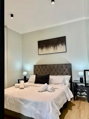 a bedroom with a large bed with white sheets at Stunning Apartment in Ellipse Waterfall Midrand in Midrand