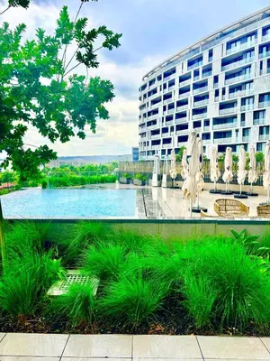 a pool with chairs and umbrellas in front of a building at Stunning Apartment in Ellipse Waterfall Midrand in Midrand