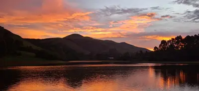 a sunset over a body of water with mountains at Bushbaby Cabin in Louwʼs Creek