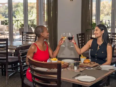 two women sitting at a table drinking wine at ANEW Hotel Centurion Pretoria in Centurion