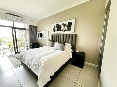 a bedroom with a large bed with white sheets at TrilogyatMenlyn in Pretoria