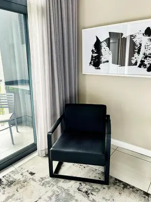 a black chair sitting in a room next to a window at TrilogyatMenlyn in Pretoria