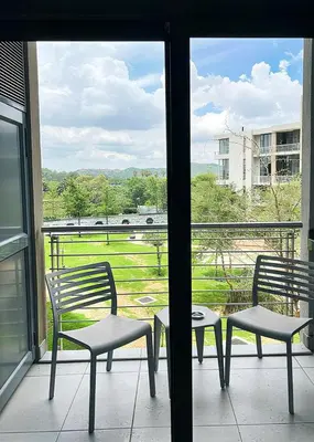 a balcony with two chairs and a table and a window at TrilogyatMenlyn in Pretoria