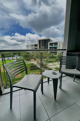 a patio with two chairs and a table on a balcony at TrilogyatMenlyn in Pretoria