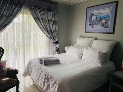 a bedroom with a white bed with a window at Ikhutseng Guesthouse in Graskop