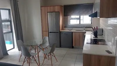 a kitchen with a table and chairs and a refrigerator at 2 Bedroom Penthouse at The Blyde in Pretoria