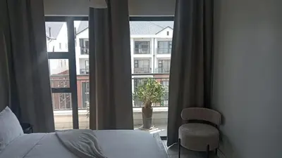 a bedroom with a bed and a chair and a window at 2 Bedroom Penthouse at The Blyde in Pretoria