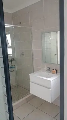 a bathroom with a sink and a shower with a mirror at 2 Bedroom Penthouse at The Blyde in Pretoria