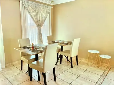 a dining room with a table and chairs and a window at Kwamakazi- The Home in Pretoria
