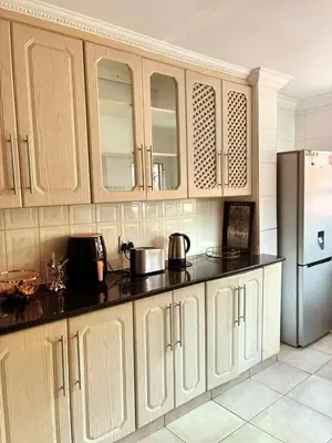 a kitchen with wooden cabinets and a refrigerator at Kwamakazi- The Home in Pretoria