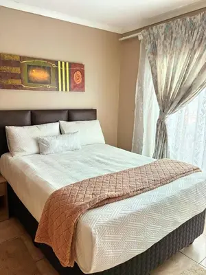 a bedroom with a large bed with a window at Kwamakazi- The Home in Pretoria