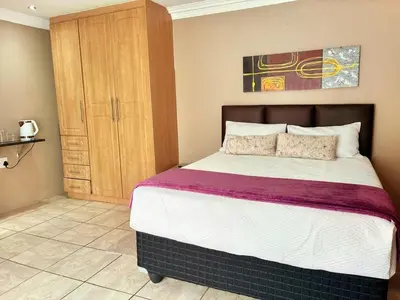 a bedroom with a bed and a wooden cabinet at Kwamakazi- The Home in Pretoria