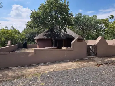 a house with a thatched roof and a fence at Out of Africa Lodge in Hartbeespoort