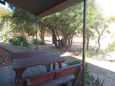 a wooden bench under a pavilion with trees at Out of Africa Lodge in Hartbeespoort