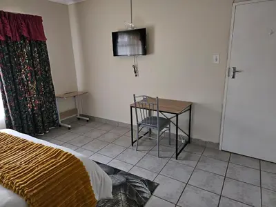 a room with a bed and a table with a chair at African Nights Barbara House in Pretoria