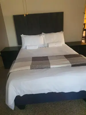 a large bed with white sheets and pillows at African Nights Barbara House in Pretoria