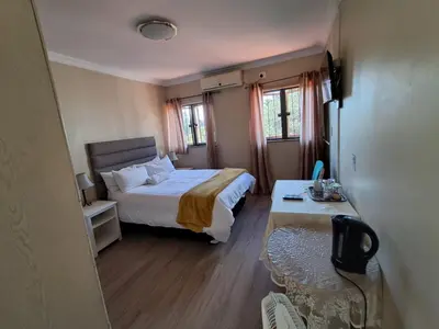 a bedroom with a bed and a table in it at African Nights Protea House in Pretoria