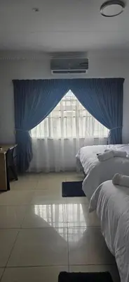 a bedroom with a large window with blue curtains at Good night guest house in Polokwane