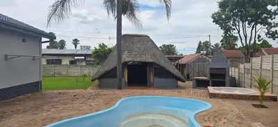 a pool in a yard with a thatch roof at Good night guest house in Polokwane