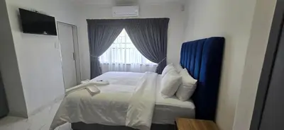 a bedroom with a bed with a blue headboard and a window at Good night guest house in Polokwane