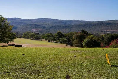 a grassy field with trees and mountains in the background at Kruger Park Lodge Unit No 440 in Hazyview