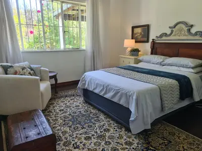 a bedroom with a bed and a chair and a window at Amourette's Cottages in Centurion