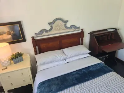 a bedroom with a bed with a wooden headboard and a desk at Amourette's Cottages in Centurion