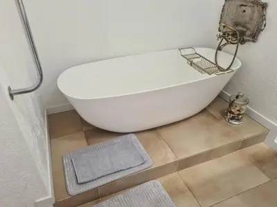 a white bath tub sitting on a floor in a bathroom at Amourette's Cottages in Centurion