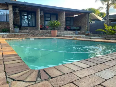 a swimming pool with blue water in front of a house at Luigi's Place in Pretoria