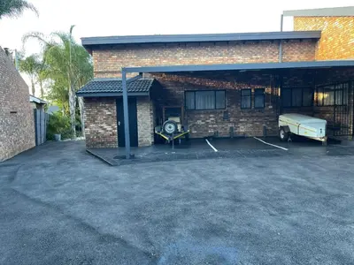 a brick building with a car parked in a parking lot at Luigi's Place in Pretoria