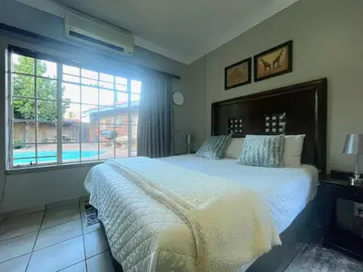 a bedroom with a large bed and a large window at Olive's Quaint in Polokwane