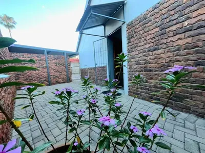 a brick building with purple flowers in front of it at Olive's Quaint in Polokwane