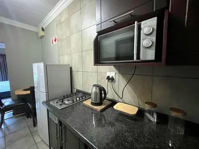 a kitchen with a stove and a microwave above it at Olive's Quaint in Polokwane