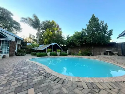 a swimming pool in a yard with a brick patio at Olive's Quaint in Polokwane