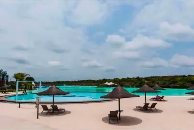 a large swimming pool with chairs and umbrellas at The Blydes Crystal Lagoon in Pretoria