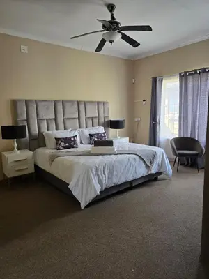 a bedroom with a large bed with a ceiling fan at Macibela2 in Bela-Bela