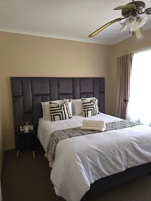 a bedroom with a large bed and a ceiling fan at Macibela2 in Bela-Bela