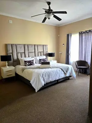 a bedroom with a large bed with a ceiling fan at Macibela2 in Bela-Bela