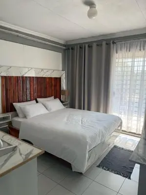 a bedroom with a large bed and a window at Amai Guesthouse in Thohoyandou