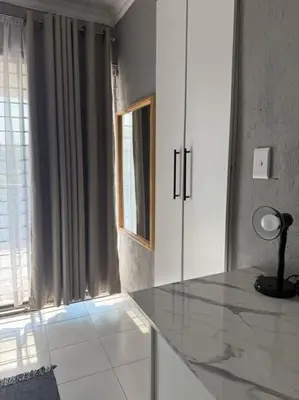 a white kitchen with a counter top and a window at Amai Guesthouse in Thohoyandou