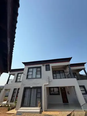 a white house with black windows on a street at Amai Guesthouse in Thohoyandou