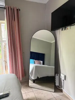 a mirror in the corner of a bedroom with a bed at La Bushka Guesthouse in Bela-Bela