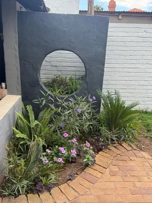 a garden with flowers in front of a building at La Bushka Guesthouse in Bela-Bela