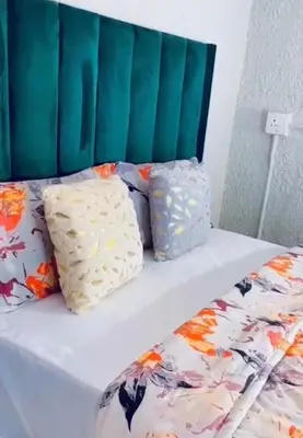 a bed with a green headboard and pillows on it at La Bushka Guesthouse in Bela-Bela