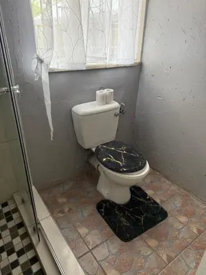 a bathroom with a toilet and a window at La Bushka Guesthouse in Bela-Bela