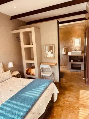 a bedroom with a large bed and a sink at Schaapkraal Cottages in Weimershoek