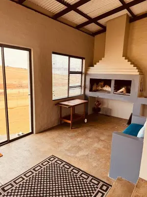 a living room with a table and a large window at Schaapkraal Cottages in Weimershoek