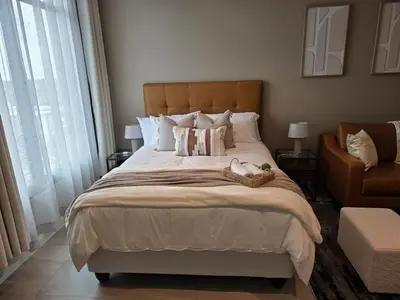 a bedroom with a large bed and a chair at Studio in Menlyn Maine in Pretoria