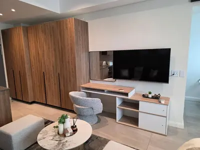 a living room with a tv and a desk with a chair at Studio in Menlyn Maine in Pretoria