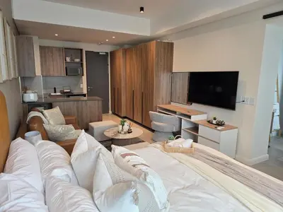 a living room with a large bed and a television at Studio in Menlyn Maine in Pretoria